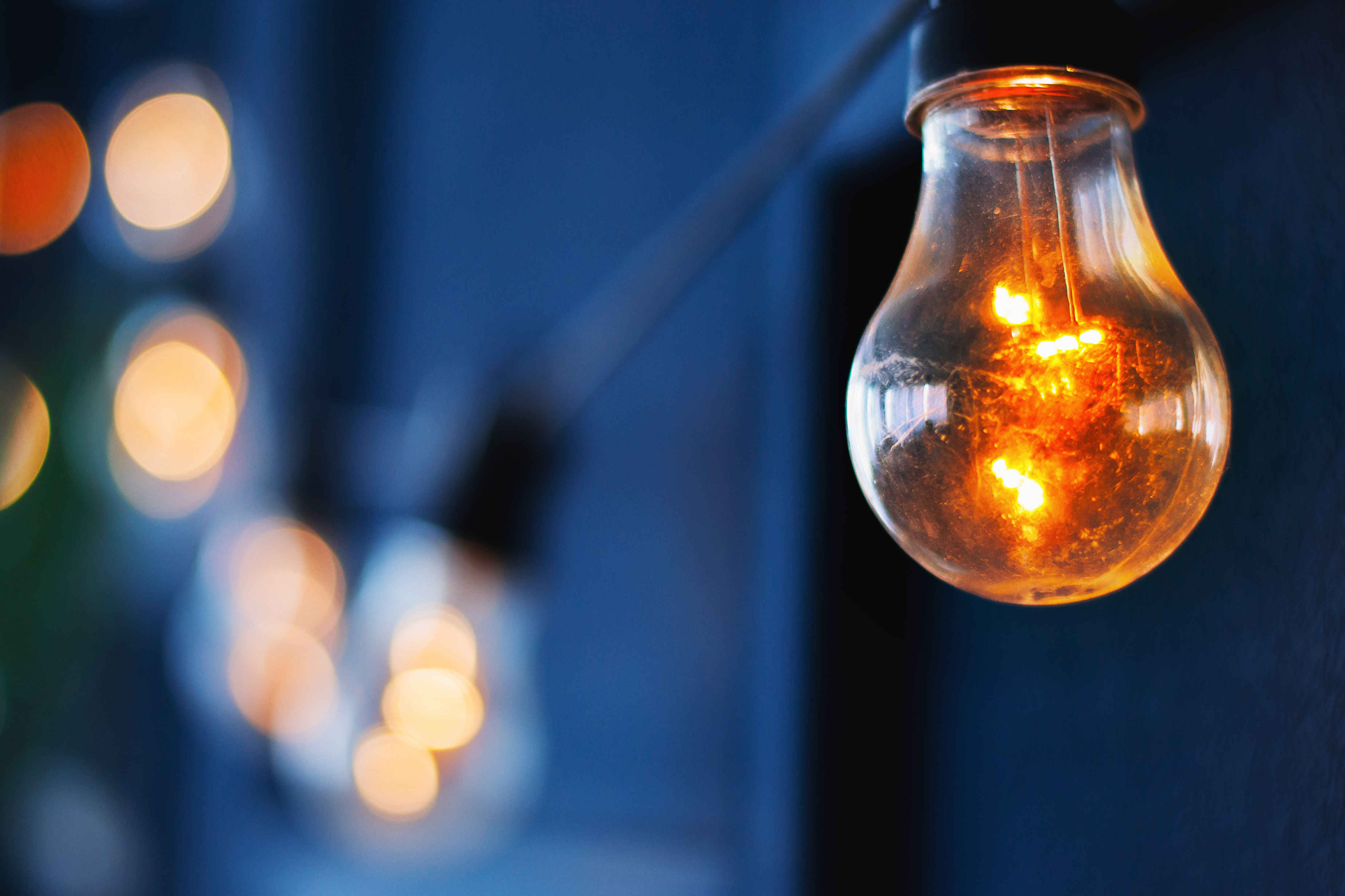 lighting bulb of Edison with a beautiful bokeh on blue background. Photo layout with copy space